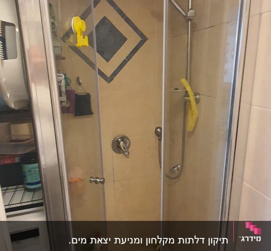 מקלחון עם דלתות זכוכית, ראש מקלחת ומדף מוצרים